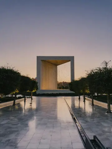 The Founders Memorial monument framed by trees and a polished walkway at dusk