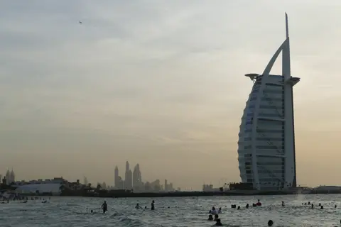 Swimmers and beachgoers at Sunset Beach near Burj Al Arab in the late afternoon