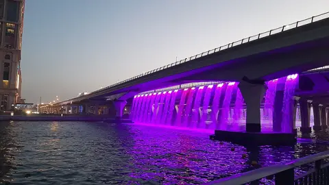 Purple lighting beneath a bridge across the canal