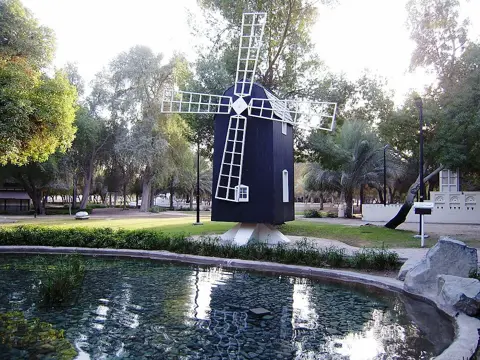 A miniature windmill beside a landscaped pond
