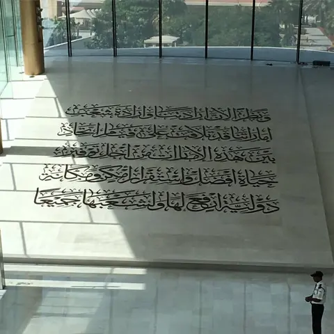 عجائب گھر میں سیڑھیوں کے پاس دیوار پر خطاطی والا متن