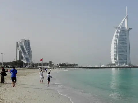 Walkers on the shoreline of Sunset Beach on a winter morning
