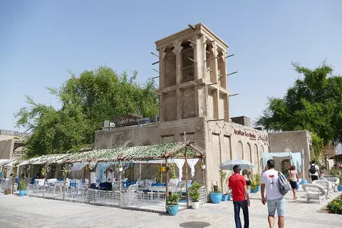 Visitors beside a traditional wind tower in the neighbourhood