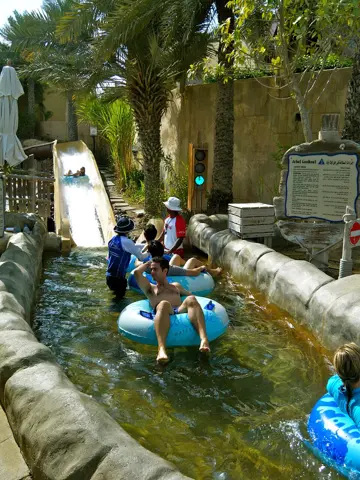 Riders on a water attraction beneath the park’s palms