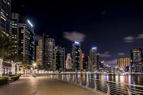 An illuminated waterside promenade after dark