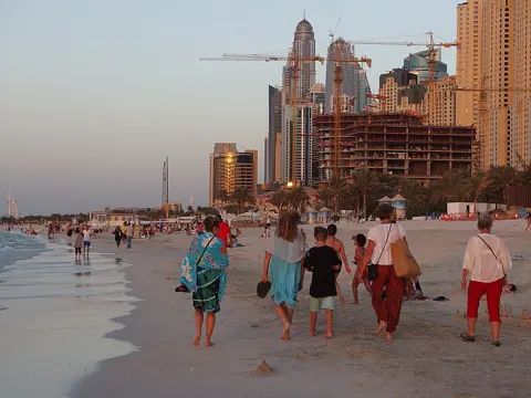 Visitors walk along the water’s edge beside the JBR towers