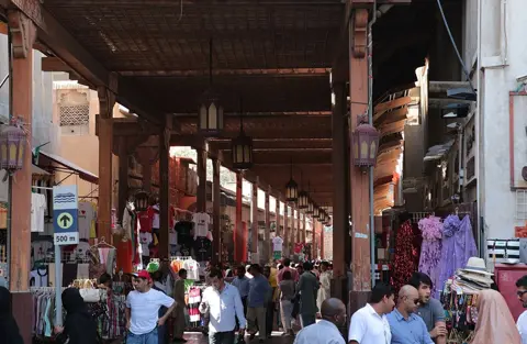 چھت دار ٹیکسٹائل سوق کی گلی سے گزرتے خریدار۔