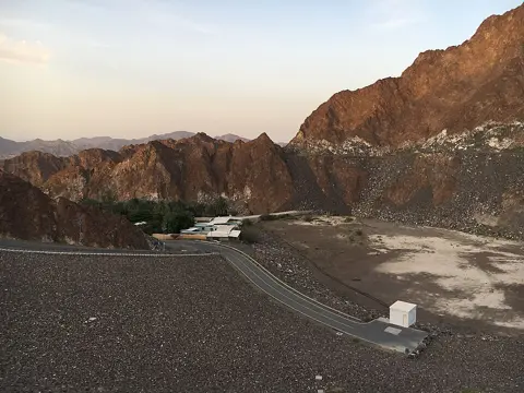 Mountain ridges and the dam’s access area at sunset