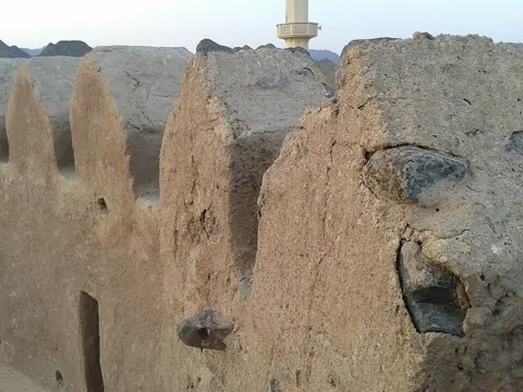دیواروں کا قریب منظر روایتی سطح کی بناوٹ اور کنگرے دکھاتا ہے۔