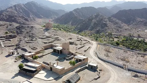 پہاڑی وادی میں قلعہ اور نگرانی برج ساتھ نظر آتے ہیں۔