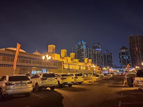 بازار کا روشن بیرونی حصہ طویل سامنے کی دیوار اور روایتی تعمیراتی تفصیل دکھاتا ہے۔