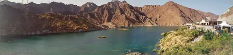 پانی کنارے کا زاویہ پتھریلی ڈھلوانوں کے سامنے پُرسکون آبی ذخیرہ دکھاتا ہے۔
