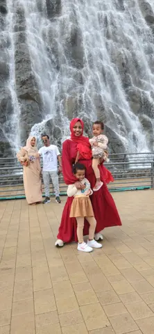 آبشار کے ساتھ زائرین بہتے پانی والی چٹان کا پیمانہ دکھاتے ہیں۔